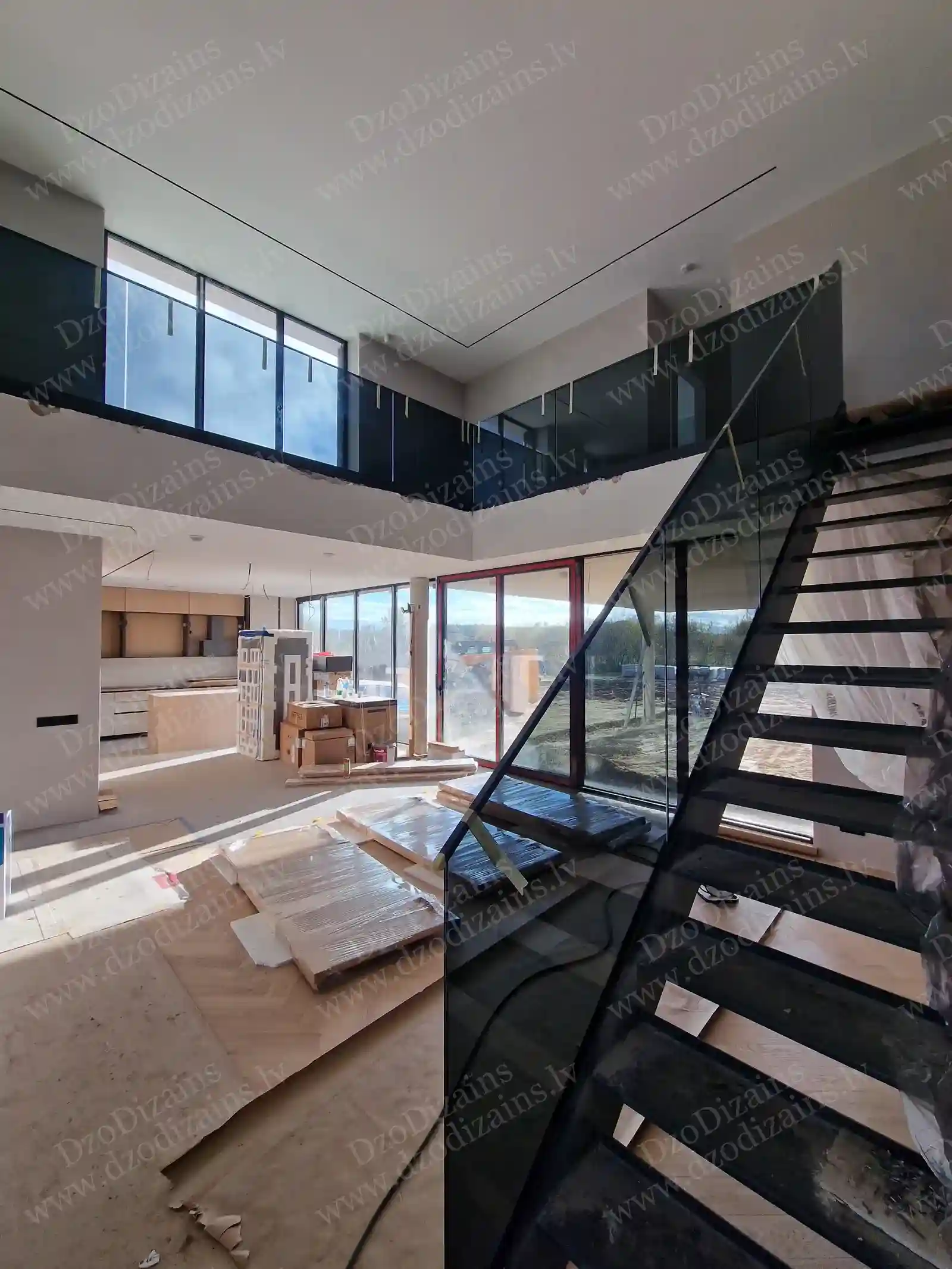 Г-образная лестница с чёрными ступенями и стеклянными перилами на этапе строительства