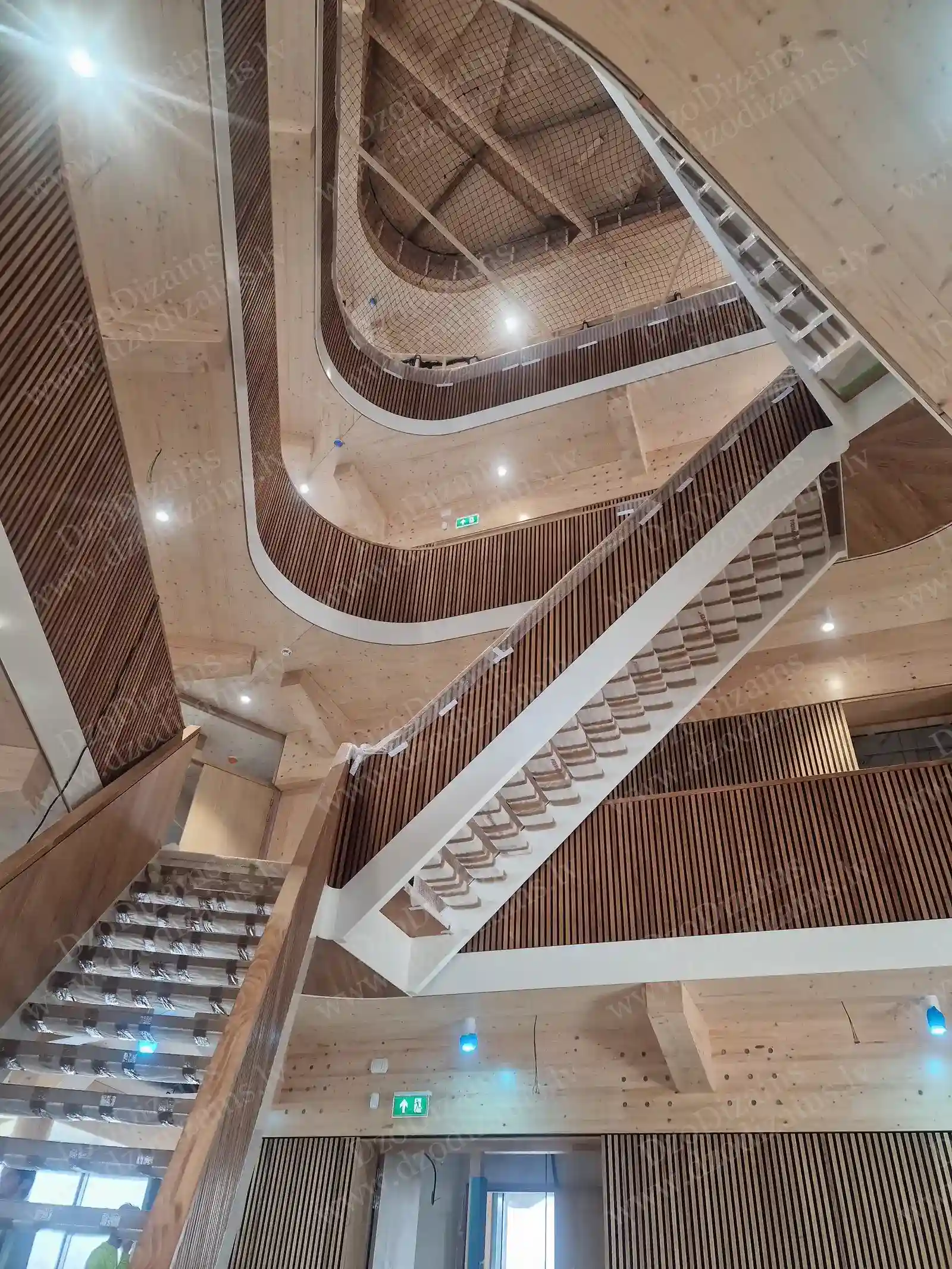 Современная деревянная лестница с изогнутой формой и вертикальными деревянными рейками на стенах