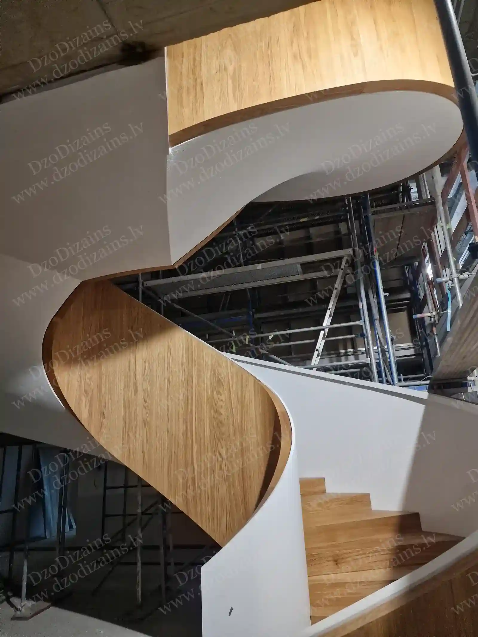 Современная винтовая лестница с деревянными панелями и белой конструкцией во время монтажа