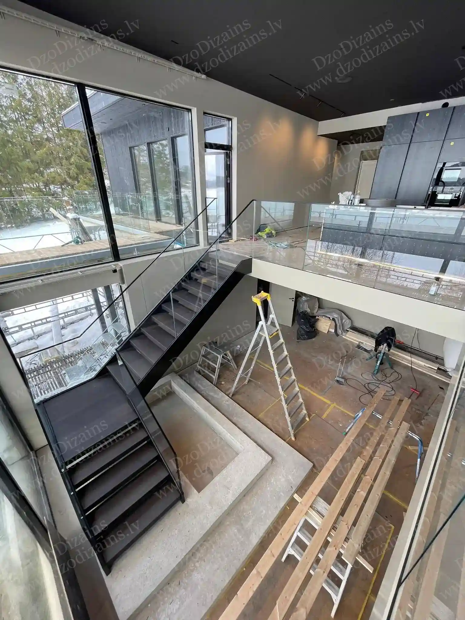 Чёрная металлическая лестница со стеклянными перилами и панорамными окнами в двухэтажном интерьере