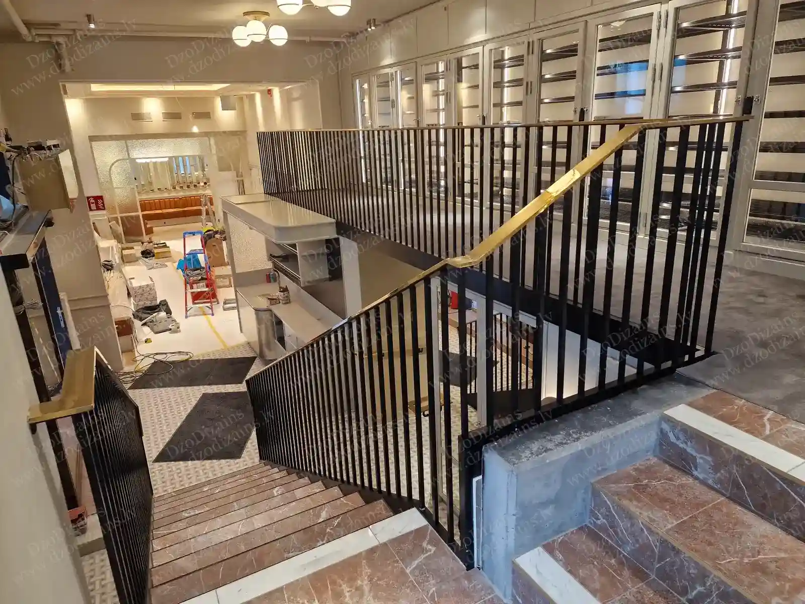 Современная лестница из чёрного металла с чёрным металлическим ограждением и элегантными полированными поручнями под латунь золотого цвета в современном интерьере на этапе ремонта